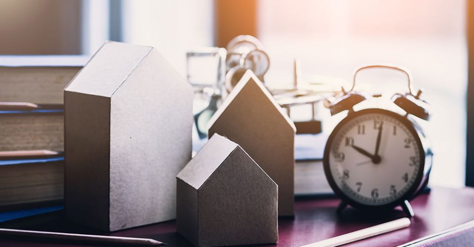 clock next to model houses on table
